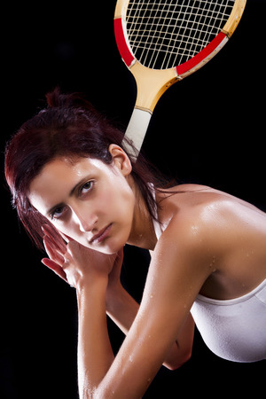 Beautiful young girl with a tennis racquet on a black background.の写真素材