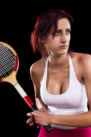 Beautiful young girl with a tennis racquet on a black background.の写真素材