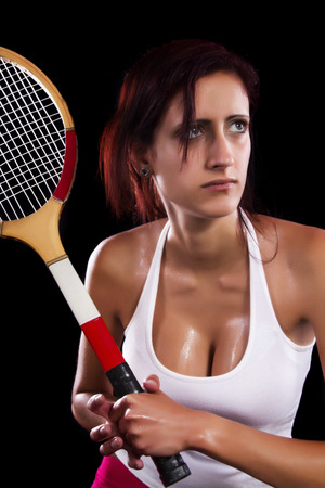 Beautiful young girl with a tennis racquet on a black background.の写真素材