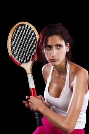 Beautiful young girl with a tennis racquet on a black background.の写真素材