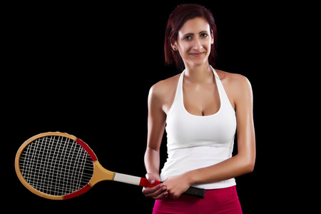 Beautiful young girl with a tennis racquet on a black background.の写真素材