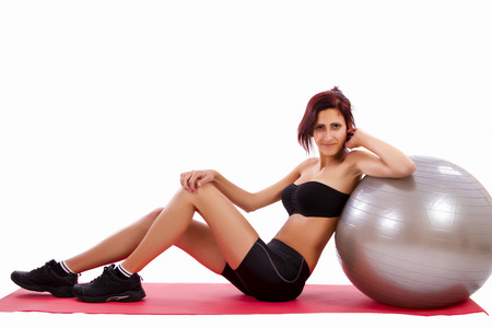 Beautiful healthy young girl with a fitness ball on a white background.の写真素材