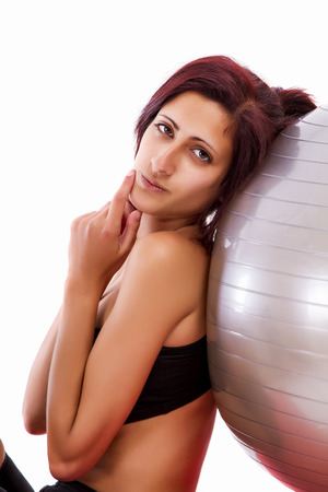 Beautiful healthy young girl with a fitness ball on a white background.の写真素材