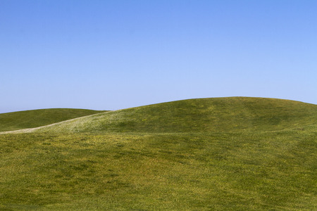 View of bare green hills with a blue sky.の写真素材