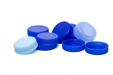 Close up view of a bunch of blue plastic caps from bottles of water isolated on a white background.