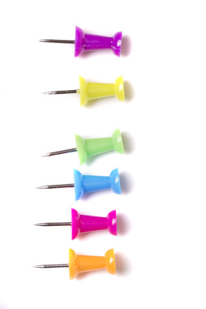 Top view of a vertical line of colorful push pins isolated on a white background.の写真素材