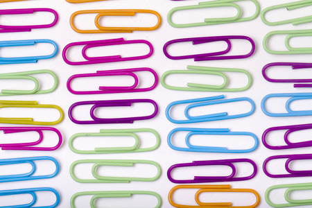 Close up view of vertical lines of colorful office paper clips isolated on a white background.の写真素材