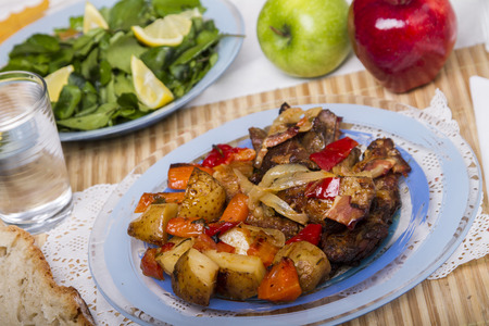 Close up view of oven baked meat with potatoes, and watercress salad.の写真素材