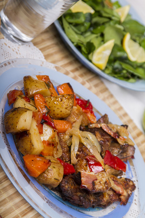 Close up view of oven baked meat with potatoes, and watercress salad.の写真素材