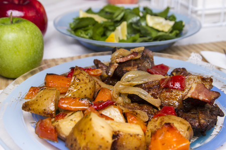 Close up view of oven baked meat with potatoes, and watercress salad.の写真素材