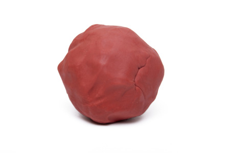 Close up view of a red plasticine ball isolated on a white background.の写真素材