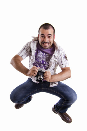 View of a young happy man jumping with a retro vintage photographic camera isolated on a white background.の写真素材