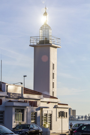 View of a small lighthouse building with sunrays creating flare on the top.の写真素材