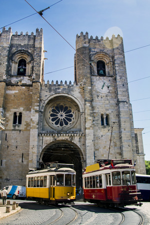 Outdoor view of the beautiful Cathedral of Se located in Lisbon, Portugal with two electrical vintage trams.のeditorial素材