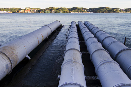 View of old sewage pipes leading to a river.の写真素材