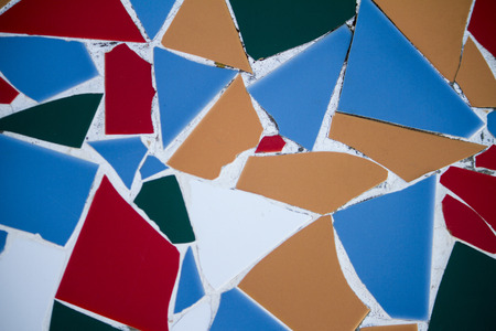 Close up view of random broken and colorful tiles on a wall.
