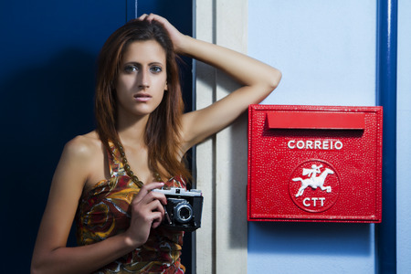 Lifestyle outdoor retro vintage young girl with a photographic camera in the city.の写真素材