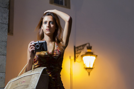Lifestyle outdoor retro vintage young girl with a photographic camera in the city.の写真素材