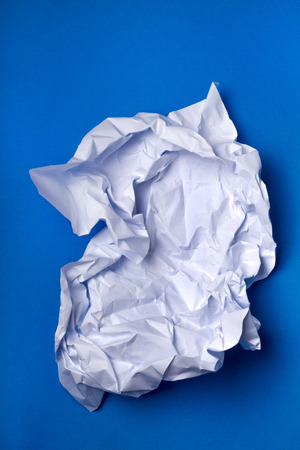 Wrinkled white piece of paper over a blue background.の写真素材