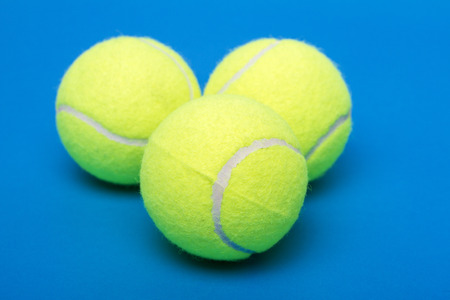 Three isolated tennis balls over a blue background.の写真素材