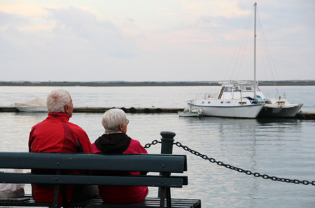 Close view of a lonely old couple on the bench gazing the ocean.の写真素材