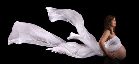 Close view of a expecting pregnant woman against a black background.の写真素材