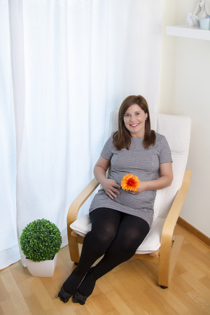 Close up view of a expecting pregnant happy woman on the comfort of her home.の写真素材