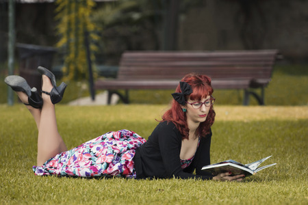 View of pinup young woman in vintage style clothing reading a book.の写真素材