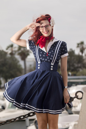 View of pinup young woman in vintage style clothing on a marina.の写真素材