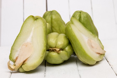 Close view of a chayote fruit on white wooden background.の写真素材