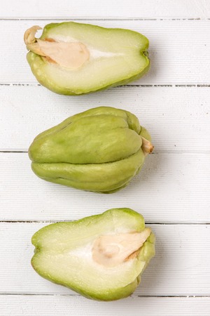 Close view of a chayote fruit on white wooden background.の写真素材