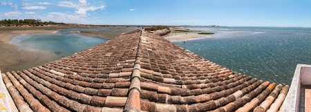 View of traditional rooftops of the Algarve region next to Ria Formosa marshlands, Portugal.の写真素材