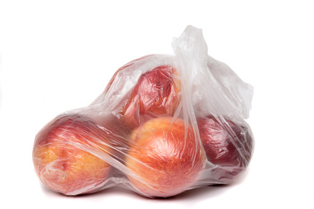 View of some peaches inside a plastic bag isolated on a white background.の写真素材