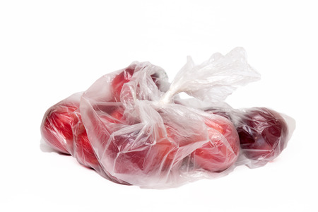 View of some plums inside a plastic bag isolated on a white background.の写真素材