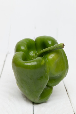 Fresh green bell pepper on a white wooden background.の写真素材