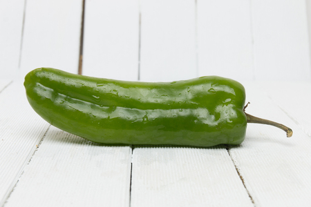 Fresh green cayenne pepper on a white wooden background.の写真素材