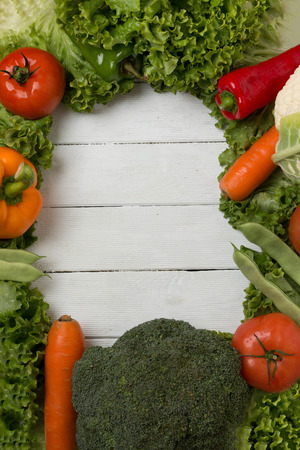 Fresh vegetables creating a frame on a white wooden background.の写真素材