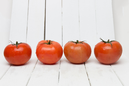 Red tomatoes fruits isolated on a white wooden background.の写真素材