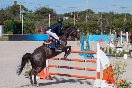 Athlete performing on a horse obstacle jumping competition.