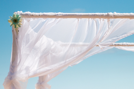 View of a simple beach wedding set frame and cloth in the wind.の写真素材