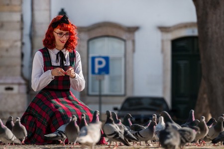 Happy pinup girl feeding the pigeons on the park.の写真素材