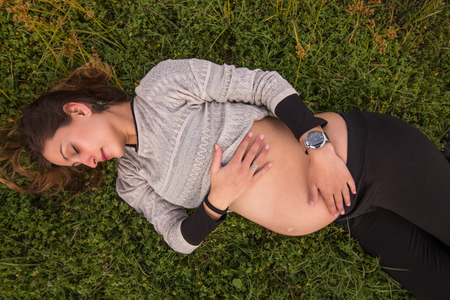 happy pregnant girl relaxing on the grass.の写真素材