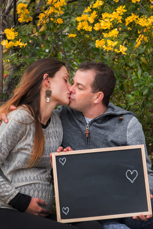 husband and pregnant wife in nature next a yellow bush plant.の写真素材