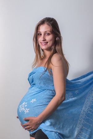 pregnant girl with blue scarf over a gray wall.の写真素材