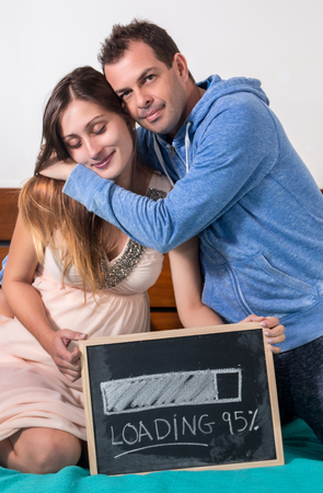 pregnant girl and husband in the bed with a black chalkboard.の写真素材