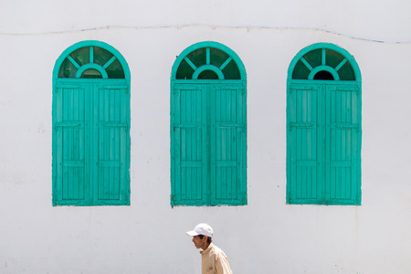 JUNE 10 ,2016 ASILAH - MOROCCO: Man walks by three big green windows in Asilah town, Morocco.のeditorial素材