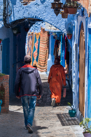 Woman in typical moroccan clothing, walking down a street in Chefchaouen city.の写真素材