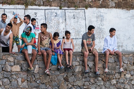CHEFCHAOUEN, MOROCCO - SEP 10, 2016: Several young kids sitting on a wall.のeditorial素材