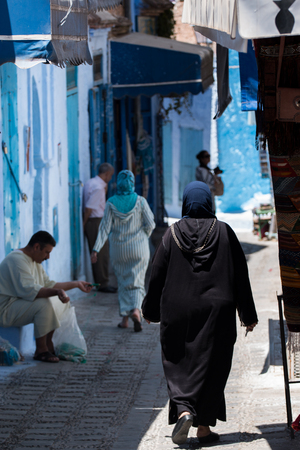 Woman in typical moroccan clothing, walking down a street in Chefchaouen city.のeditorial素材