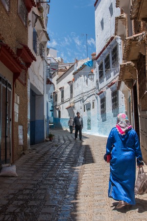 Women in typical moroccan clothing, walking down a street in Chefchaouen city.のeditorial素材
